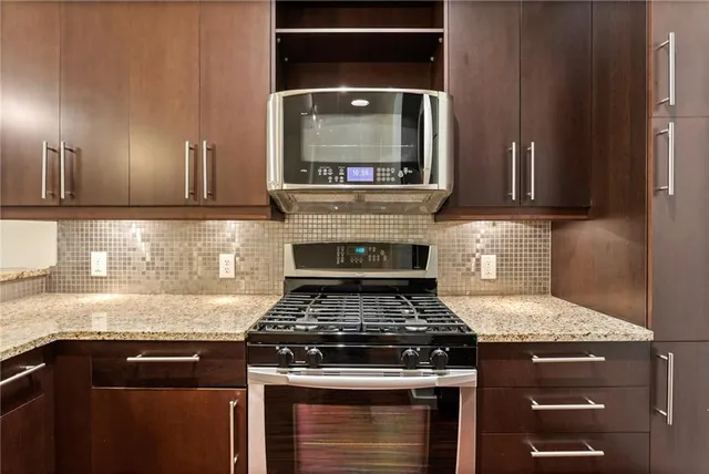 a kitchen with granite countertop a stove top oven microwave and cabinets