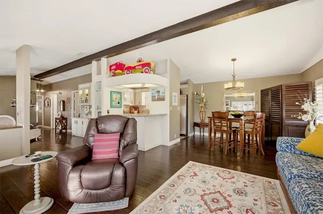 a living room with furniture a rug and a dining table with wooden floor
