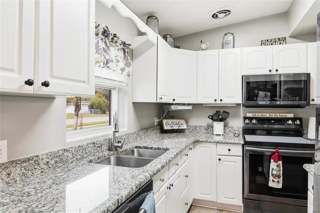 a kitchen with stainless steel appliances kitchen island granite countertop a refrigerator and microwave