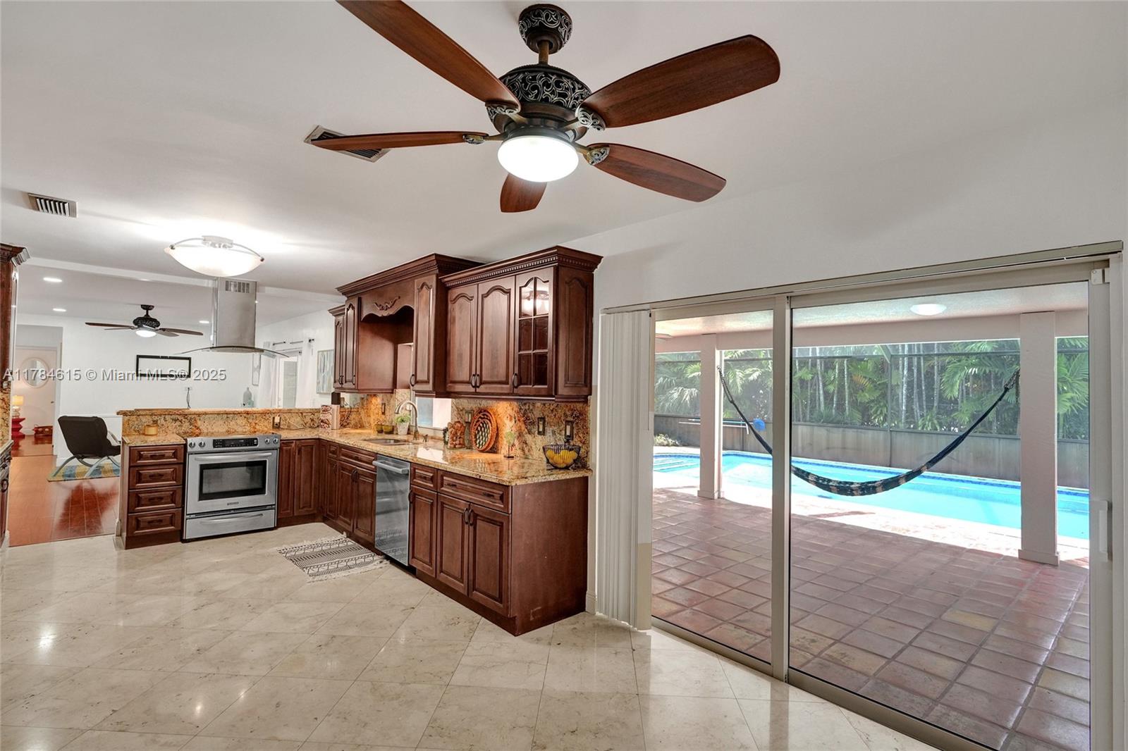 7360 Southwest 120th Street Pinecrest, FL 33156 - Photo 12 of 68 a large kitchen with stainless steel appliances granite countertop a stove and a view of living room