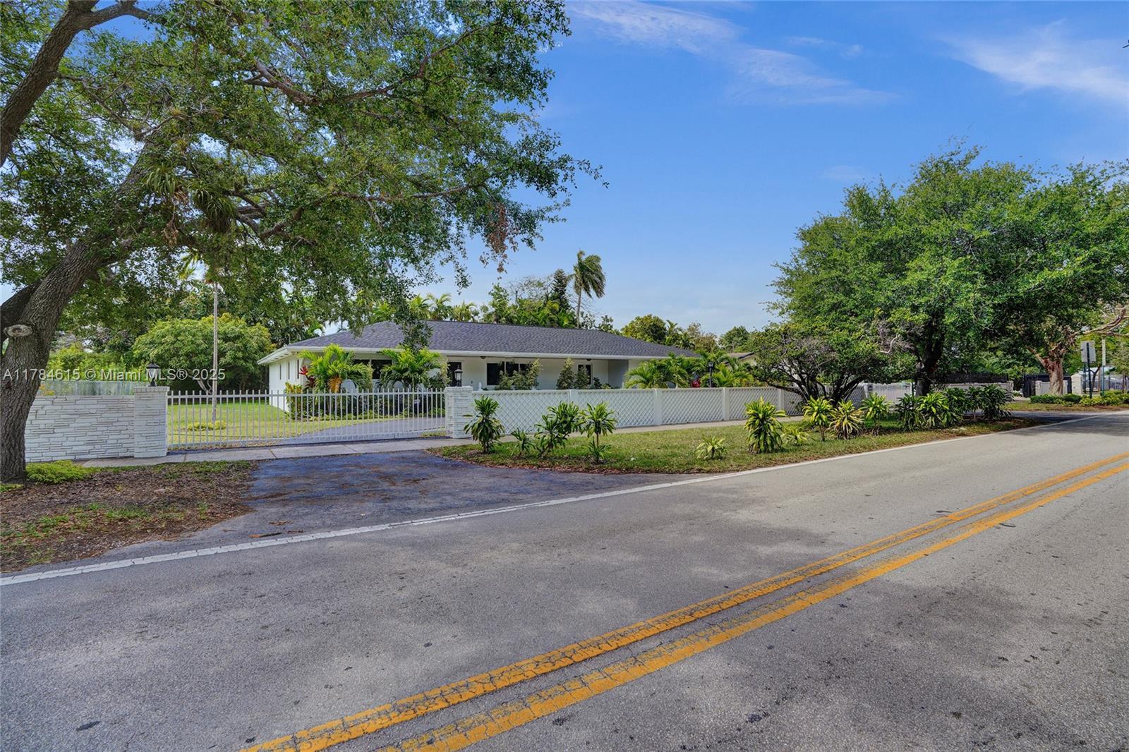 7360 Southwest 120th Street Pinecrest, FL 33156 - Photo 68 of 68 a front view of a house with a yard and potted plants