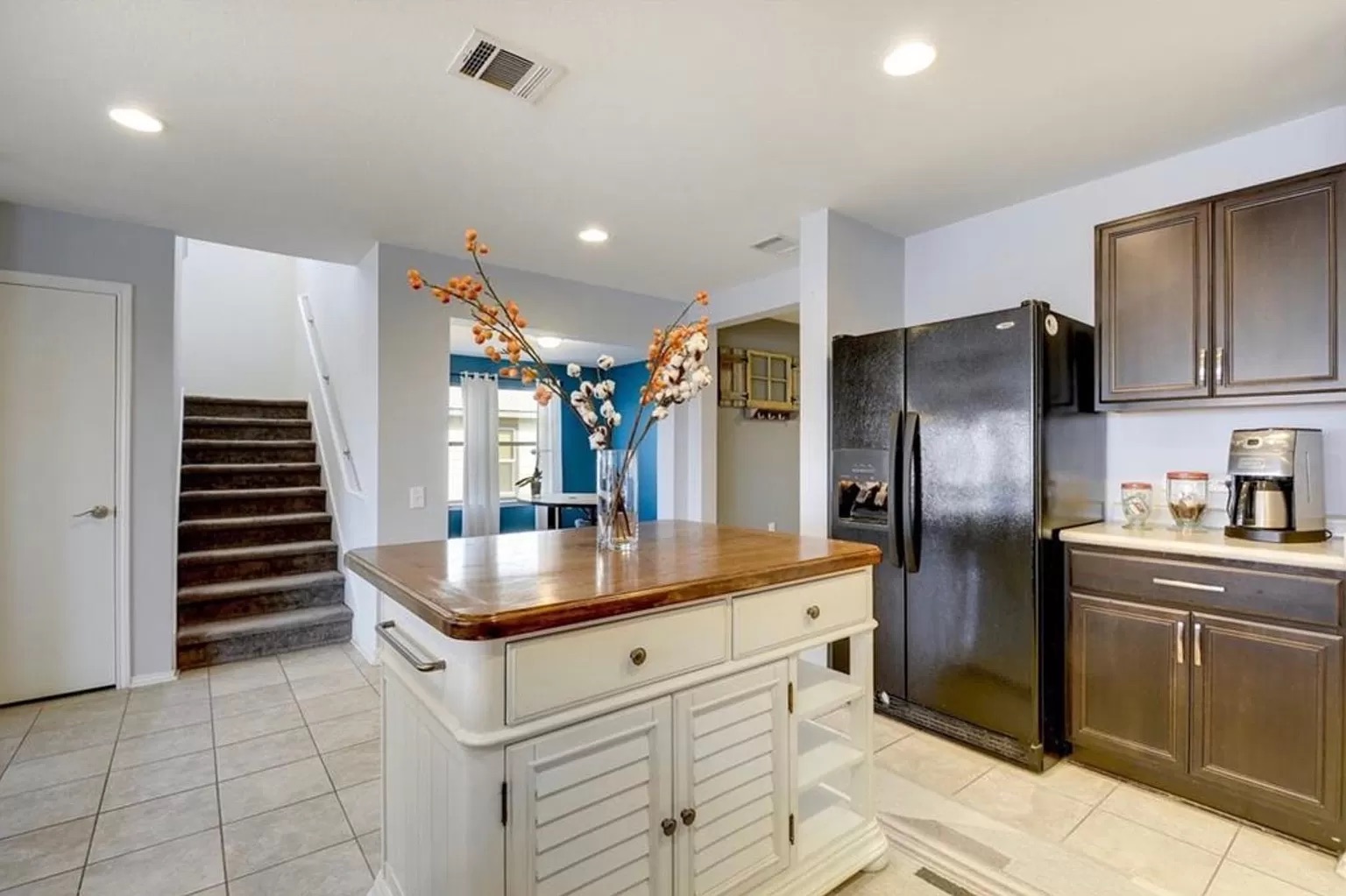9016 Ridgewell Road Austin, TX 78747 - Photo 9 of 30 A well-lit kitchen with a central island seamlessly connects to a carpeted staircase and an adjacent living area.
