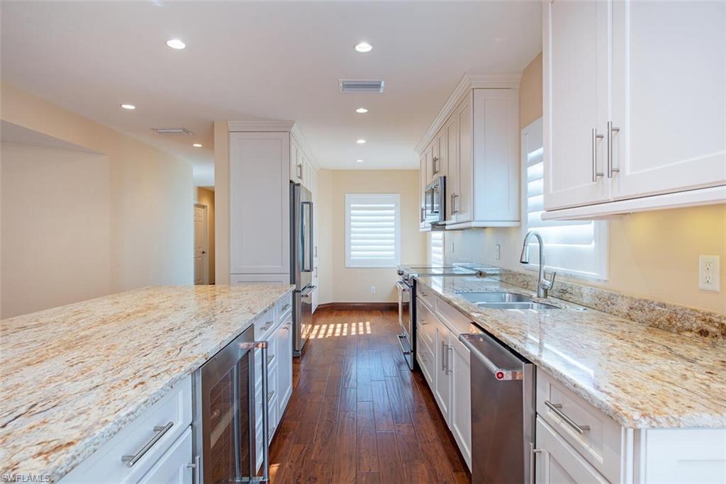 808 Rue Deville, Unit 35 Naples, FL 34108 - Photo 15 of 20 Kitchen with light stone countertops, white cabinets, beverage cooler, stainless steel appliances, and recessed lighting