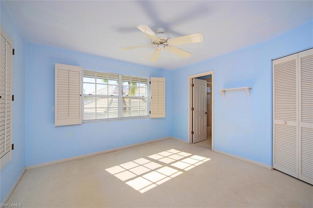 808 Rue Deville, Unit 35 Naples, FL 34108 - Photo 16 of 20 2nd floor ensuite bedroom featuring a closet, a ceiling fan, and light colored carpet
