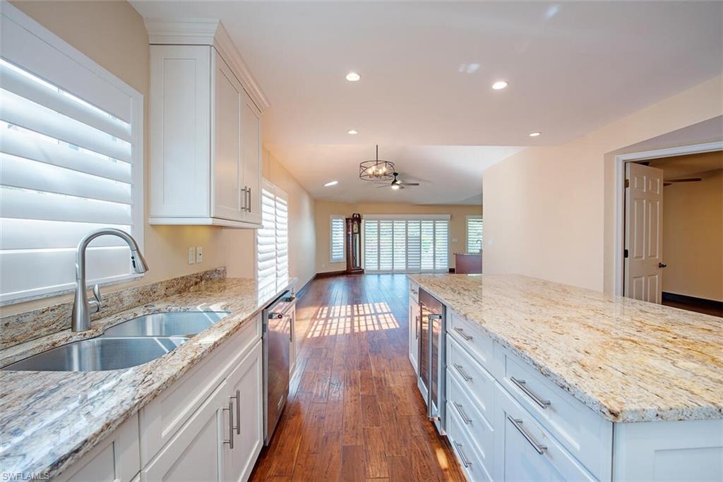 Kitchen featuring a center island, white cabinetry, light stone countertops, recessed lighting, and dark wood-style floors