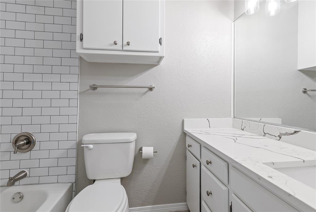 304 Moore Creek Road, Unit 300 Hurst, TX 76053 - Photo 15 of 17 Bathroom featuring a white subway tile surround, a white vanity with a patterned countertop, and a built-in medicine cabinet