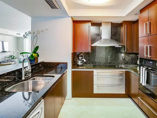 a kitchen with kitchen island granite countertop a sink a stove and refrigerator