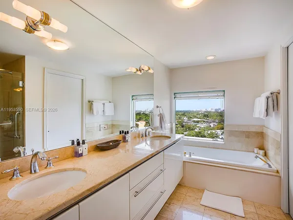 a bathroom with a tub a sink and a large mirror