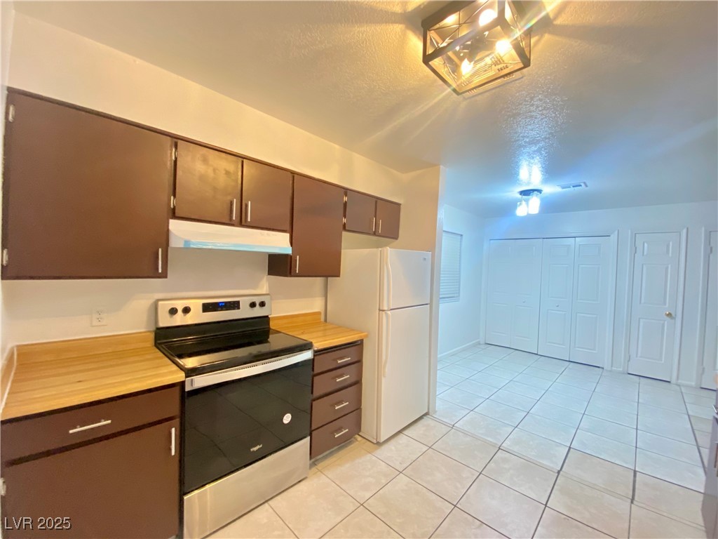 5284 Hagemann Lane, Unit D Las Vegas, NV 89110 - Photo 3 of 30 Kitchen with electric stove, a textured ceiling, light tile patterned flooring, light countertops, and under cabinet range hood