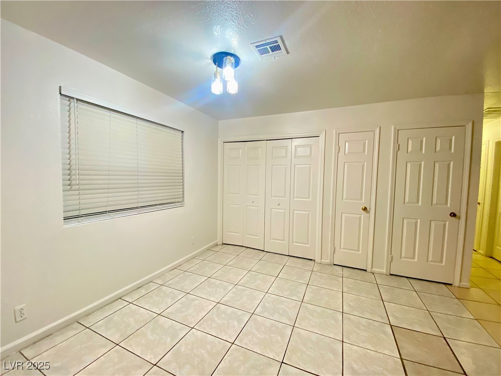 5284 Hagemann Lane, Unit D Las Vegas, NV 89110 - Photo 9 of 30 Unfurnished bedroom with light tile patterned floors and a closet