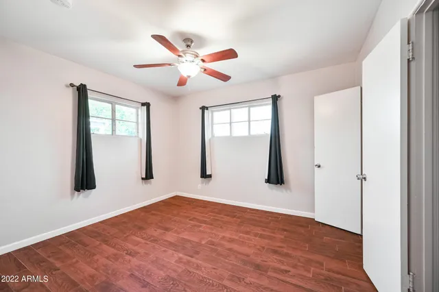 a view of empty room with wooden floor and fan