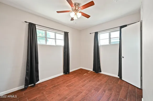 a view of a room with a ceiling fan and wooden floor