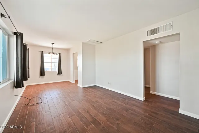 a view of a big room with wooden floor and windows