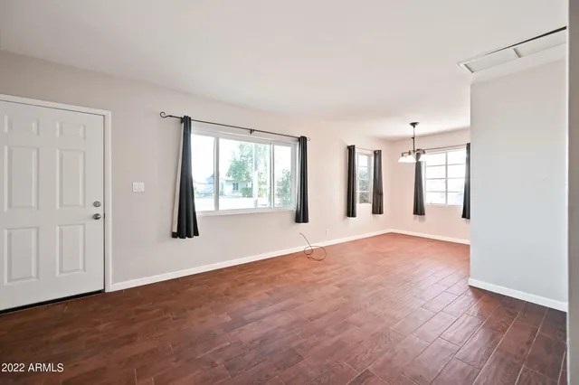 a view of an empty room with a window and wooden floor