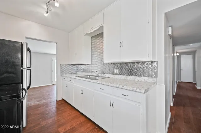 a bathroom with a granite countertop sink a mirror and shower