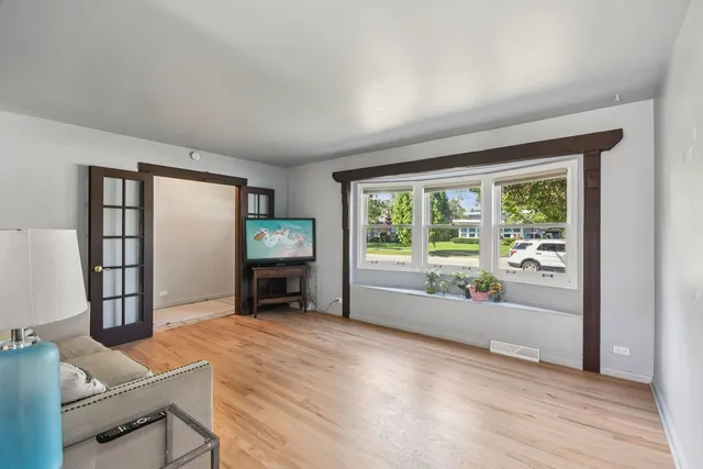 a view of an empty room with a window and wooden floor