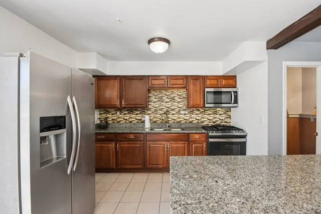 a kitchen with stainless steel appliances granite countertop a stove refrigerator and sink
