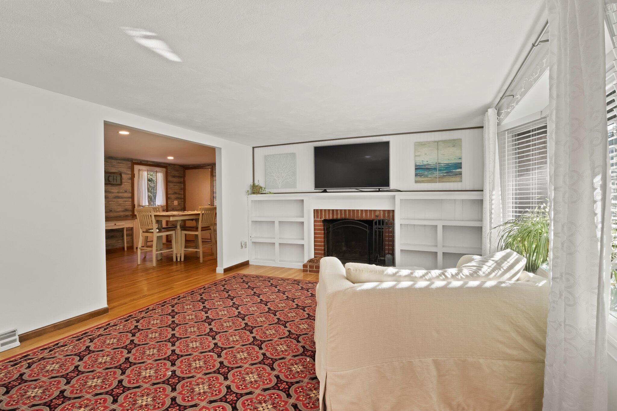 270 Mashpee Neck Road Mashpee, MA 02649 - Photo 12 of 36 a living room with furniture a fireplace and a flat screen tv