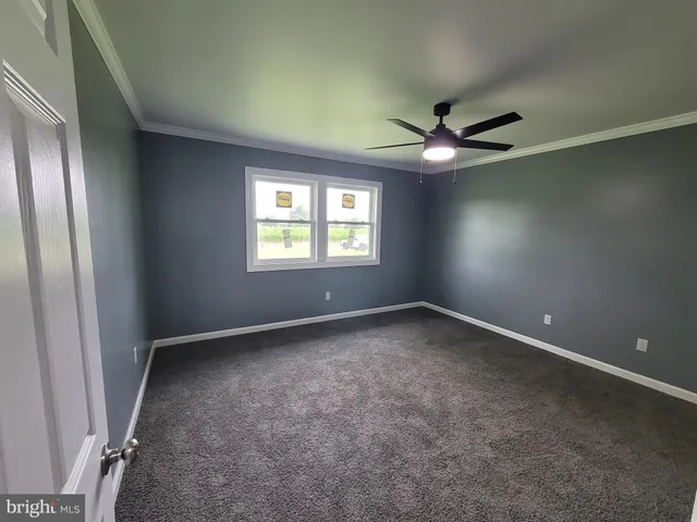an empty room with a window and a fan