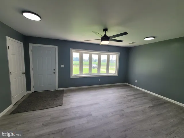 an empty room with chandelier fan and windows