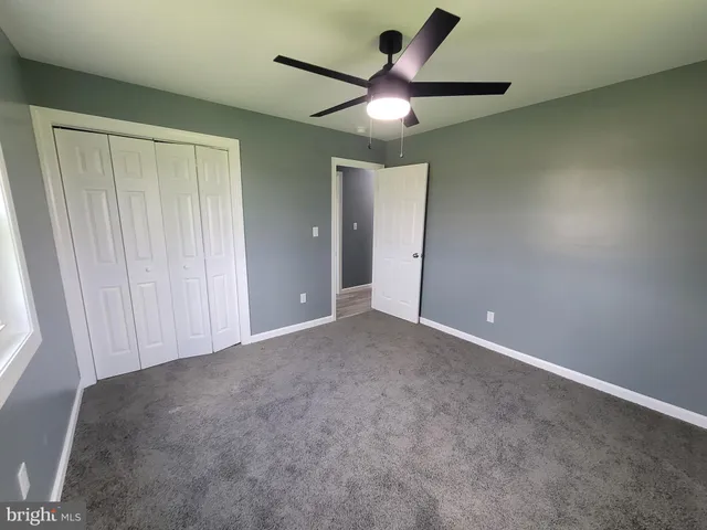 an empty room with a ceiling fan and window