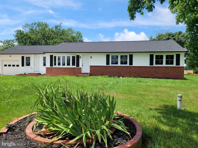 a front view of a house with a yard and potted plants