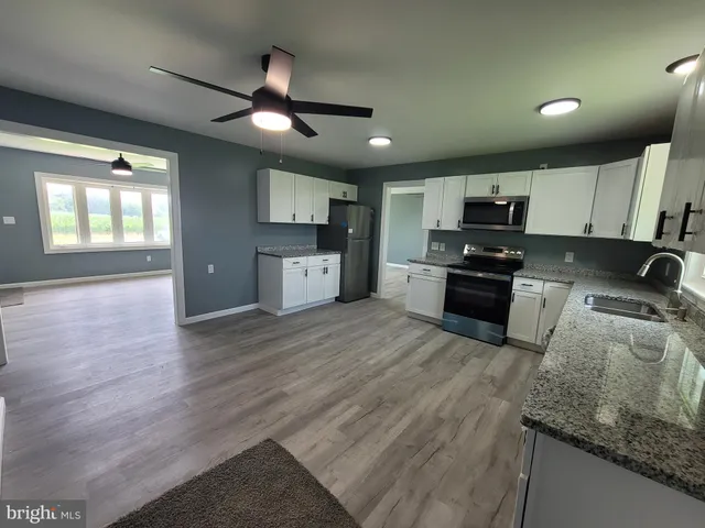 a kitchen with stainless steel appliances granite countertop a sink a stove top oven a counter space and cabinets