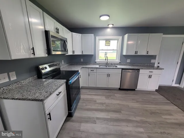 a kitchen with stainless steel appliances granite countertop a sink stove and cabinets