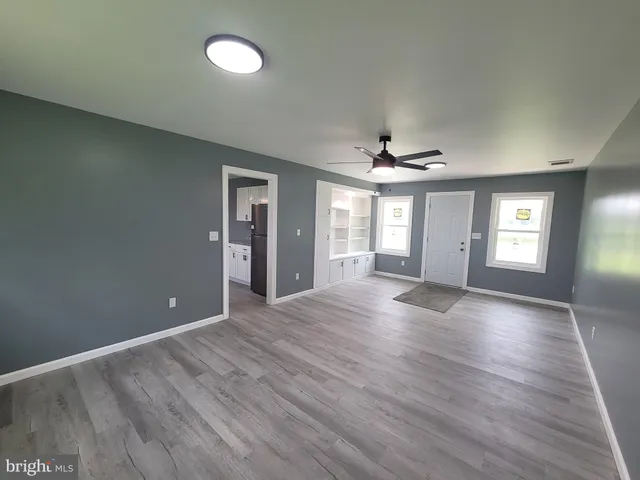 a view of an empty room with window and wooden floor