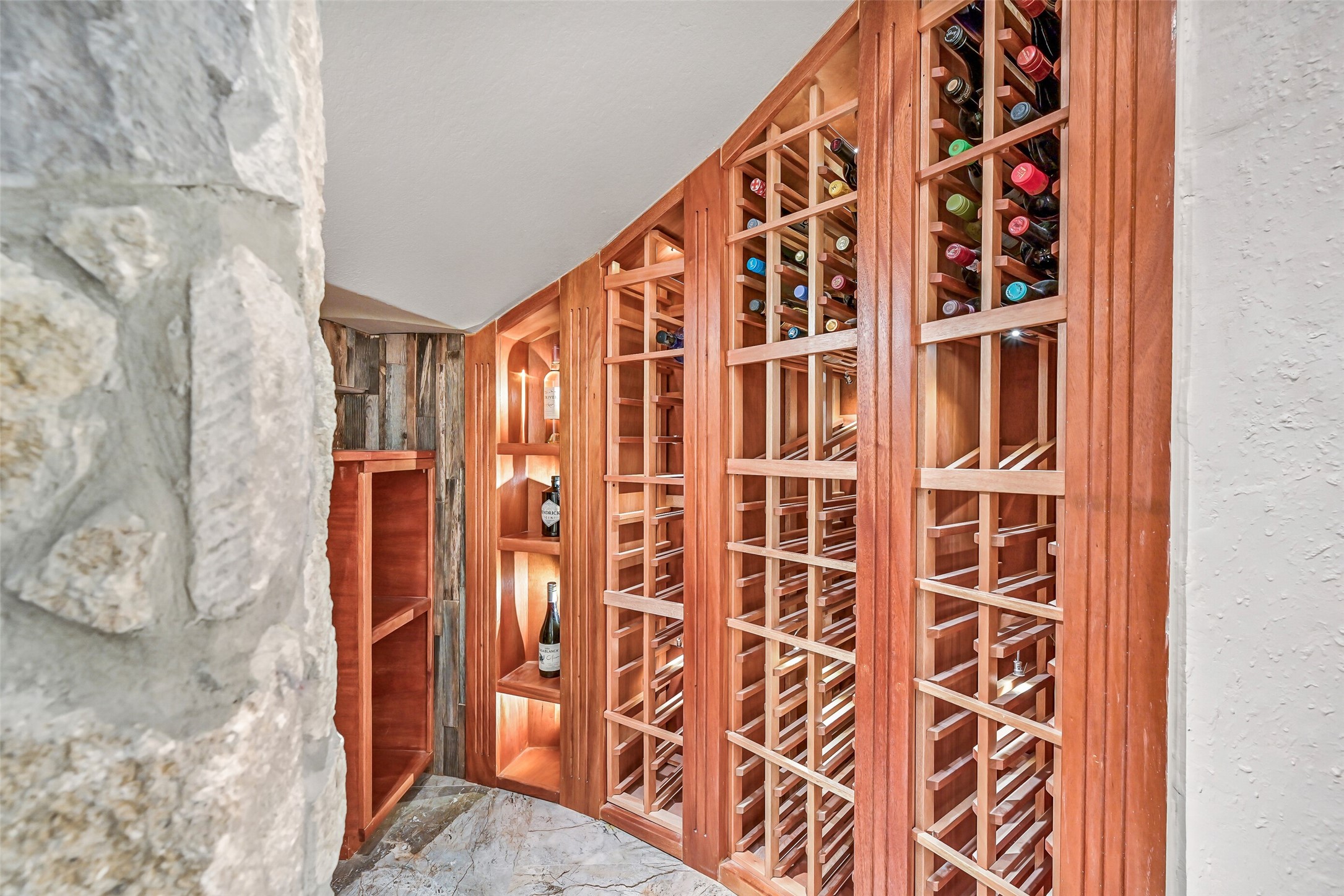 1008 Point Isabel Lane Friendswood, TX 77546 - Photo 7 of 50 Tucked beneath the staircase, discover a thoughtfully designed wine grotto with custom wood bottle storage, display shelving, and ambient lighting for both function and visual appeal.