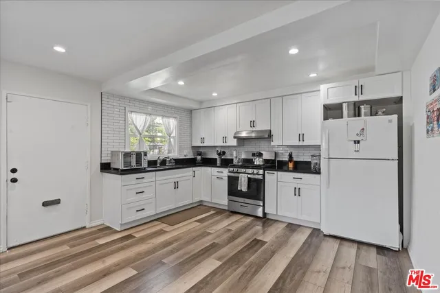 a kitchen with granite countertop white cabinets and white appliances