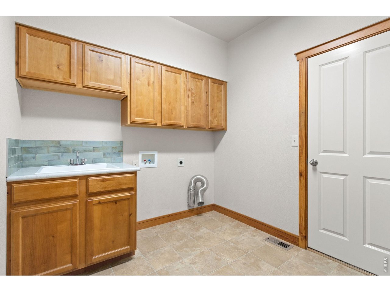 4226 Rolling Gate Road Fort Collins, CO 80526 - Photo 24 of 37 Main floor laundry room with built-in cabinetry, sink, and updated tile backsplash.