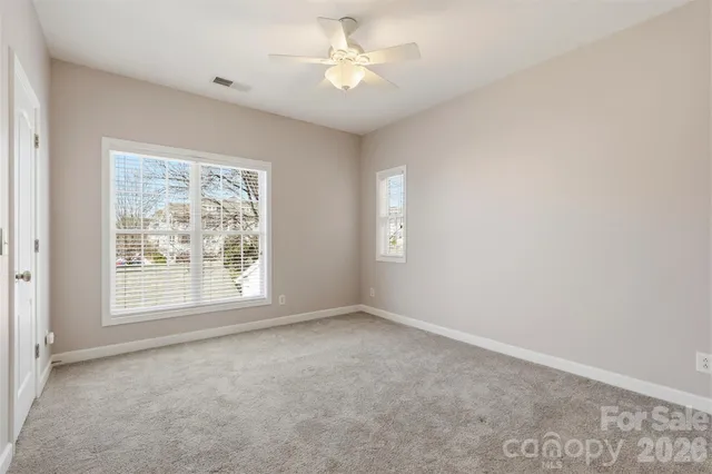 an empty room with windows and fan