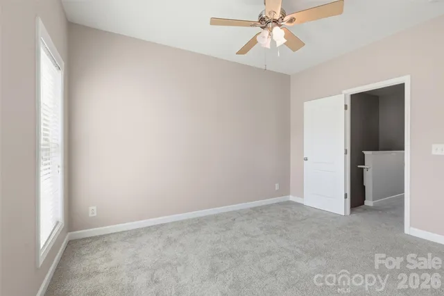 an empty room with closet and a chandelier fan