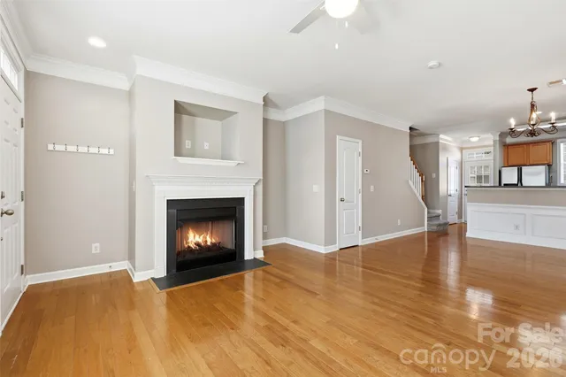 a view of an empty room with wooden floor fireplace and a window