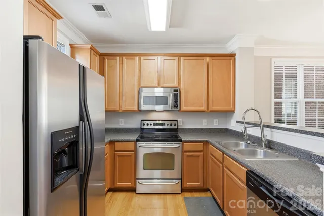 a kitchen with granite countertop a refrigerator stove and sink