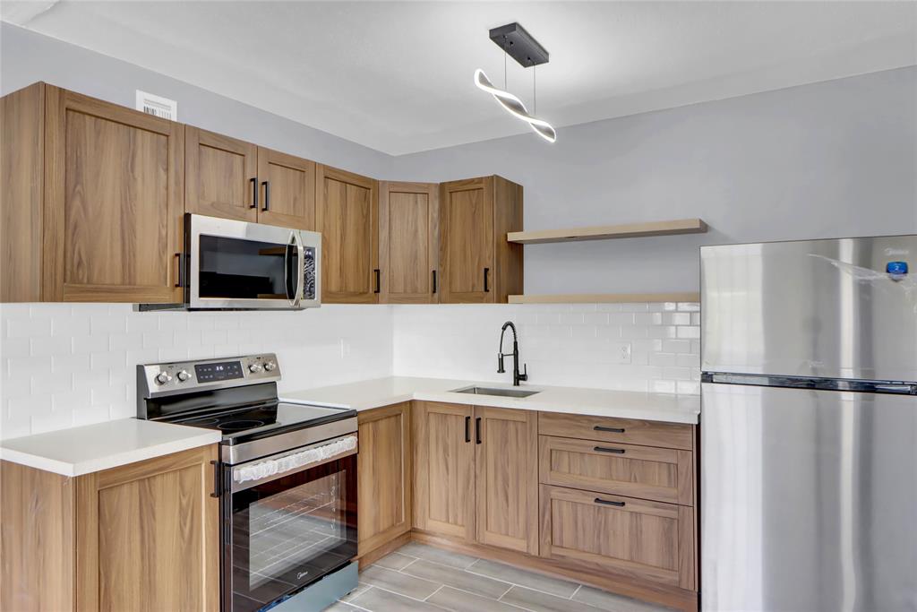 a kitchen with a sink and a stove top oven with wooden floor