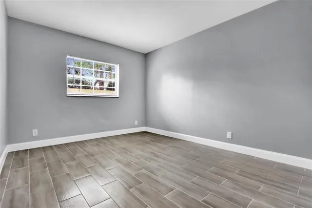 a view of an empty room with wooden floor and a window