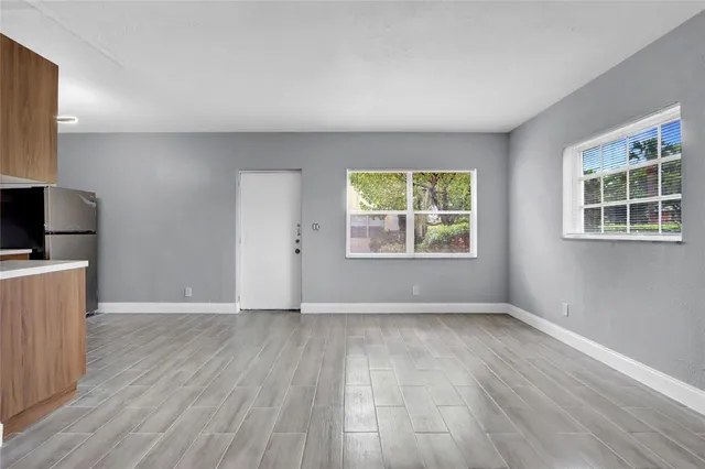 a view of an empty room with wooden floor and a window