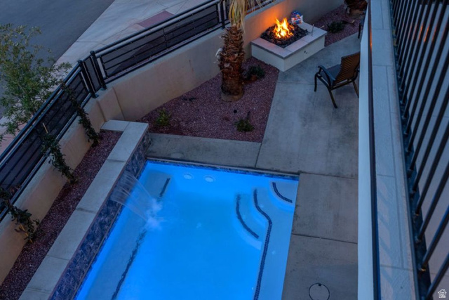 2600 Ocotillo Way, Unit 31 Santa Clara, UT 84765 - Photo 67 of 73 Outdoor space featuring a luminous swimming pool with a waterfall feature, a built-in fire pit, paved patio areas, and a rock-landscaped bed with a mature palm