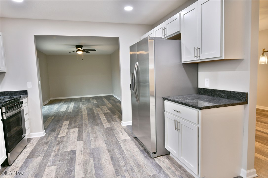 Kitchen featuring white cabinets, wood finished floors, appliances with stainless steel finishes, and ceiling fan