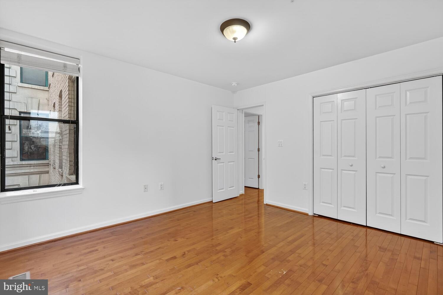 2627 Adams Mill Road Northwest, Unit 104 Washington, DC 20009 - Photo 15 of 16 a view of an empty room with wooden floor and a window