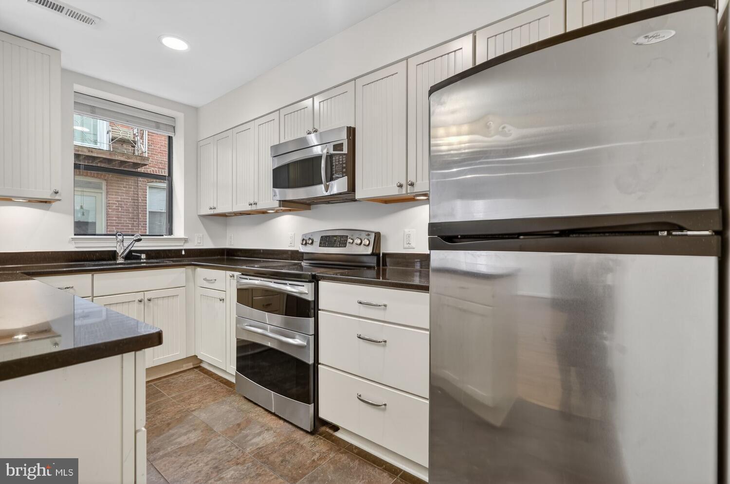 2627 Adams Mill Road Northwest, Unit 104 Washington, DC 20009 - Photo 4 of 16 a kitchen with white cabinets and white appliances