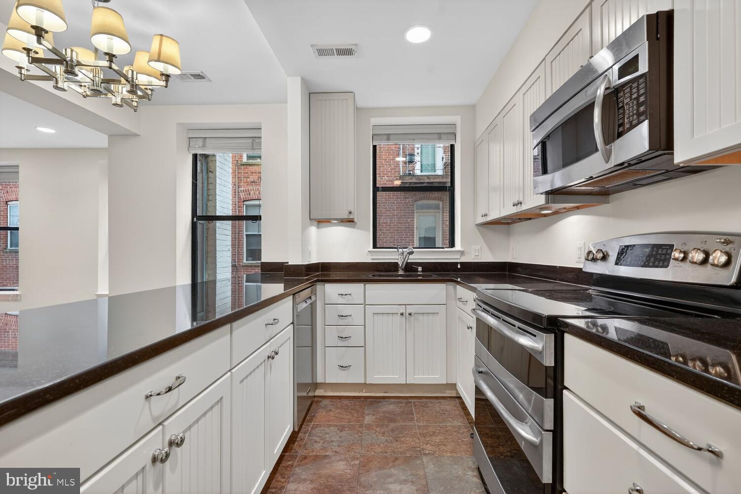 2627 Adams Mill Road Northwest, Unit 104 Washington, DC 20009 - Photo 5 of 16 a kitchen with granite countertop white cabinets and stainless steel appliances