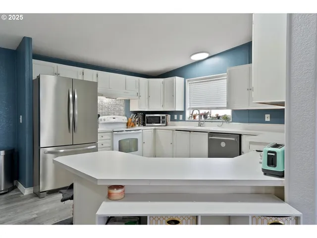 a kitchen with kitchen island a white counter top space cabinets and stainless steel appliances