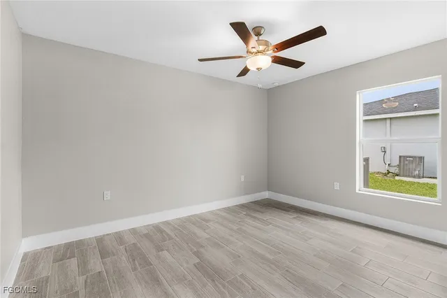 an empty room with window and ceiling fan
