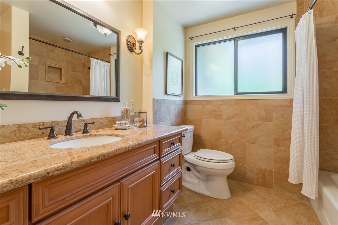 3500 West Commodore Way Seattle, WA 98199 - Photo 15 of 25 a bathroom with a granite countertop toilet sink and a mirror