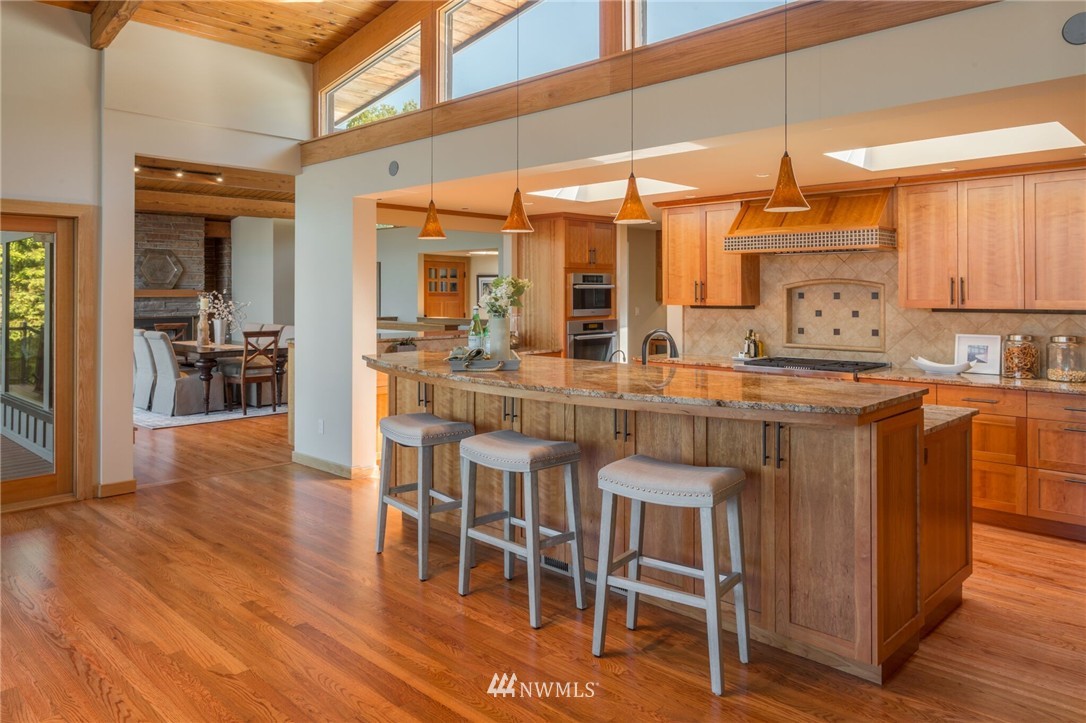 3500 West Commodore Way Seattle, WA 98199 - Photo 6 of 25 a kitchen with stainless steel appliances granite countertop a stove top oven a sink a dining table and chairs with wooden floor