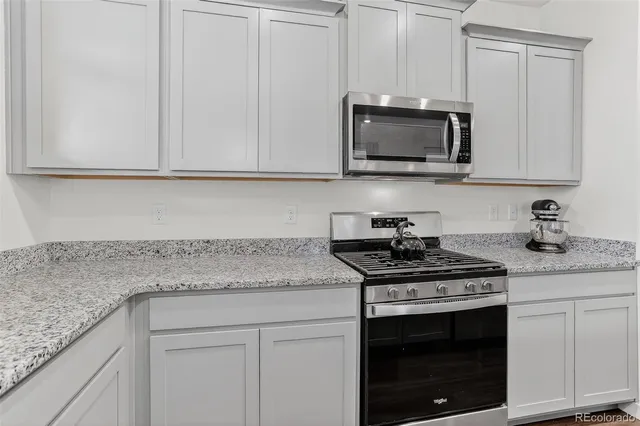 a kitchen with granite countertop white cabinets and a stove with a sink