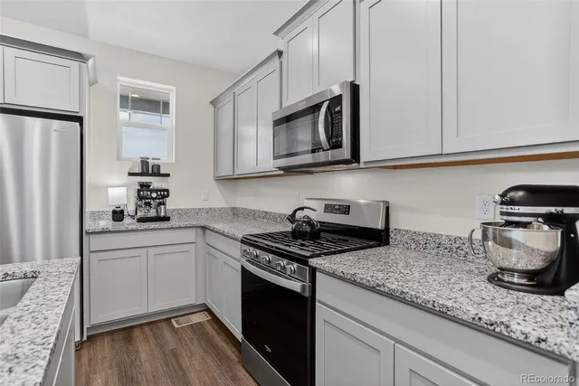 a kitchen with granite countertop cabinets stainless steel appliances and wooden floor